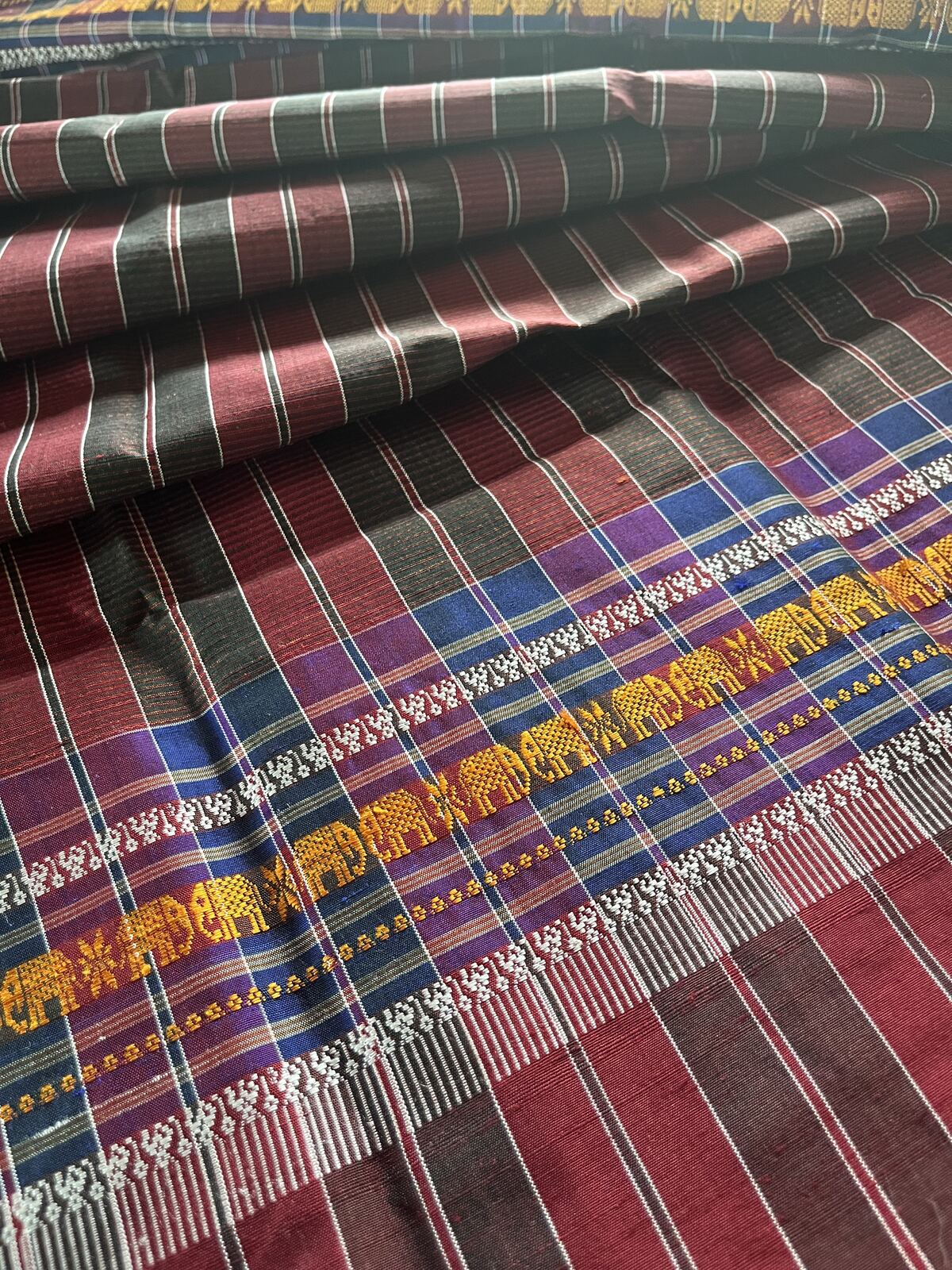 Folded maroon and black sabai crossed by rows of small golden elephants